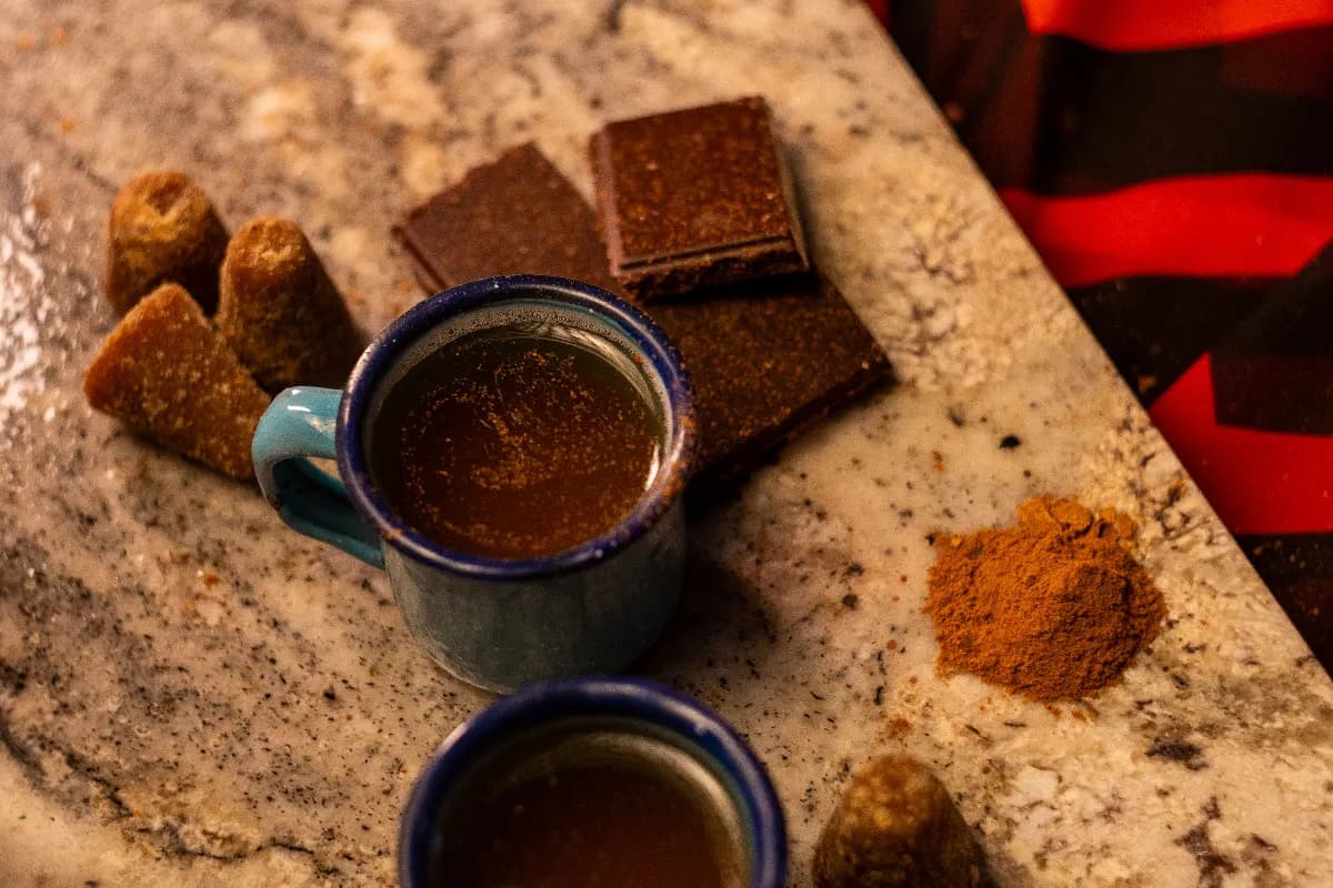 Diferentes endulzantes naturales sobre una mesa de cocina: miel, stevia, piloncillo, jarabe de agave, dátiles y azúcar mascabado en frascos y cucharas.