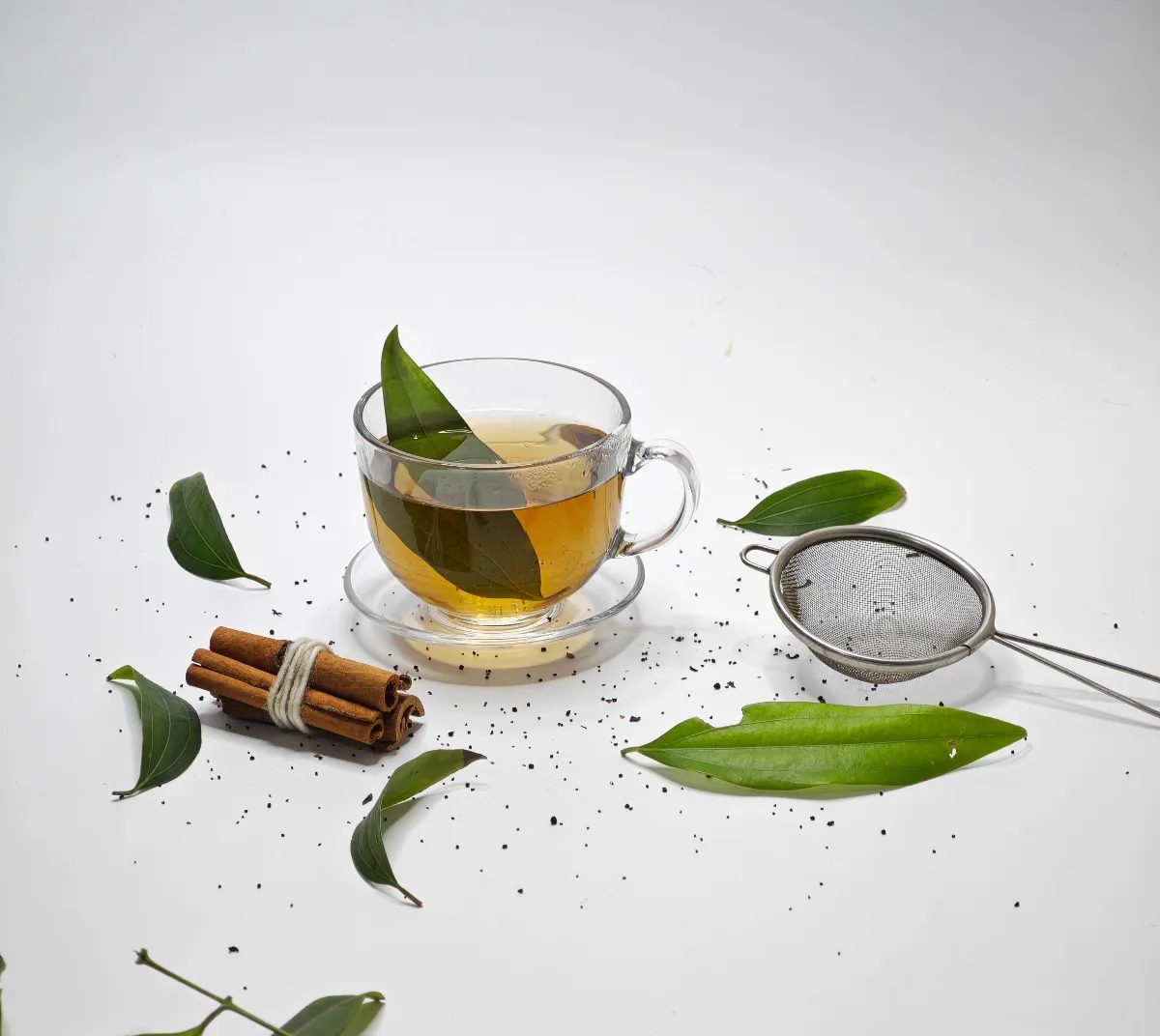Hojas frescas de llantén junto a una taza de infusión natural.